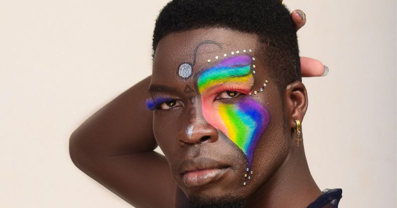 A photo shows a close-up of Kenyan LGBTQ+ activist Edwin Chiloba wearing rainbow and glitter makeup with his hand behind his head