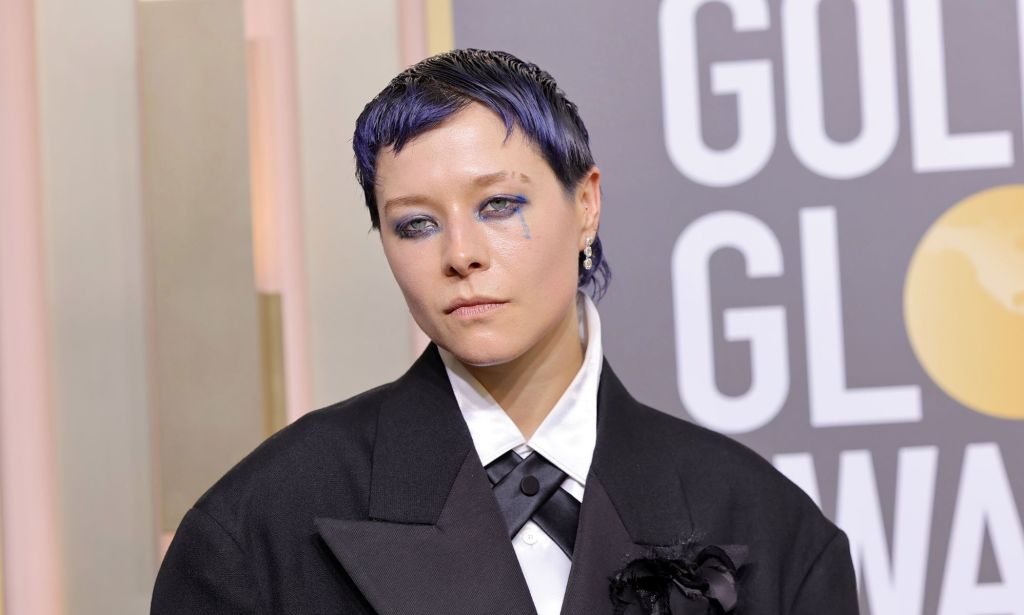 Actor Emma D'Arcy on the Golden Globes red carpet wearing a black suit with cropped purple hair.