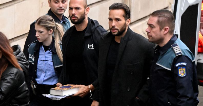 A photo shows controverisal influencer Andrew Tate and his brother Tristan Tate dressed in black arrive handcuffed and escorted by police at a courthouse in Bucharest