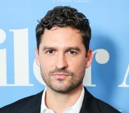 Knock at the Cabin star Ben Aldridge poses in front of a blue background