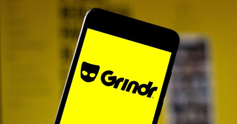 A phone showing a yellow depiction of the Grindr logo.