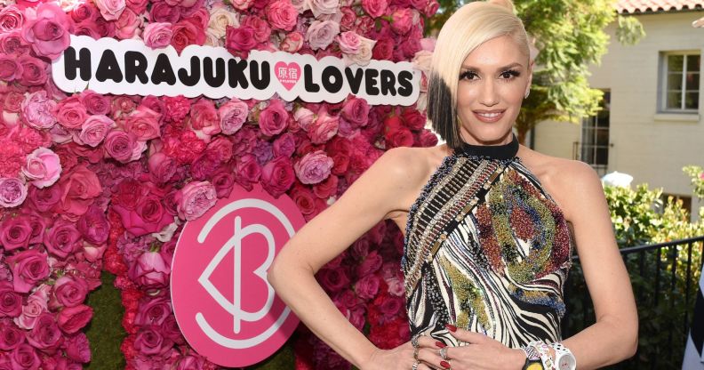 Pop star Gwen Stefani stands in front of the logo for her perfume collection Harajuku Lovers, against a backdrop of pink roses.