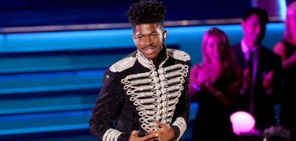 Lil Nas X performs at the 2022 Grammy Awards in a black and silver jacket.