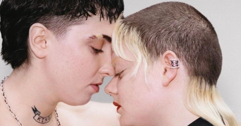 Two models rest their head on one another affectionately.