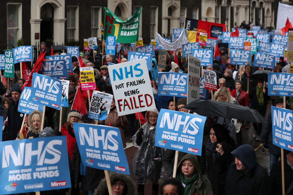 Protestors carry placards during a march calling for an end to the "crisis" in the state-run National Health Service (NHS), in central London on February 3, 2018.