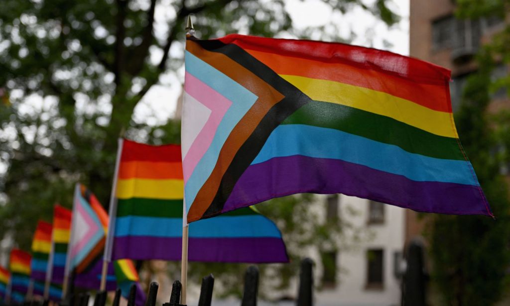 LGBTQ+ progress flags wave in an American street.