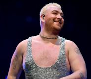 Sam Smith smiling while performing at the 2022 Jingle Bell Ball wearing a silver glittery jumpsuit