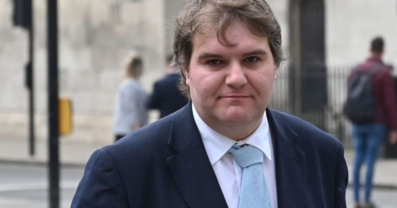 Jamie Wallis wears a white shirt, light blue tie and dark blue jacket while standing outside