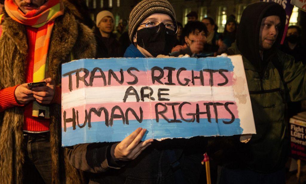 A protestors holds up a sign reading 'trans rights are human rights.'