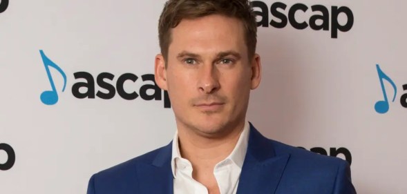 Lee Ryan in a blue suit with white open collar shirt