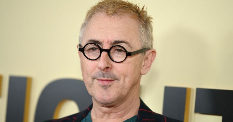 Alan Cumming in black glasses with blonde hair