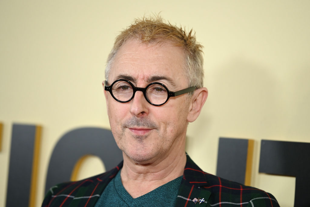 Alan Cumming in black glasses with blonde hair