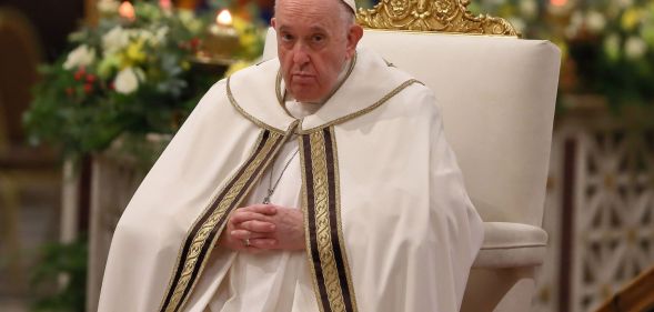 Pope Francis wears his white cassock while he sits on a white and gold chair during mass