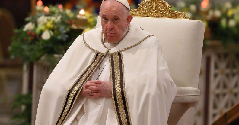 Pope Francis wears his white cassock while he sits on a white and gold chair during mass