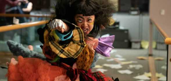 Stephanie Hsu as Joy throwing a punch, with her face painted in clown make-up