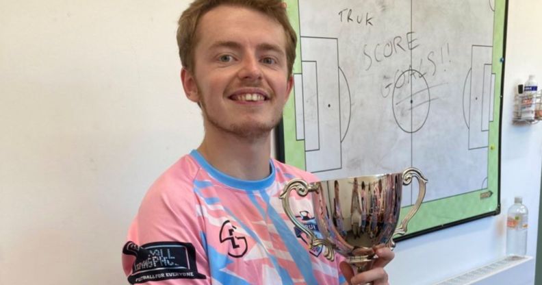 Arthur Webber holds up a trophy as he wears the TRUK United FC football kit, and he is set to captain the club's first all-trans men team