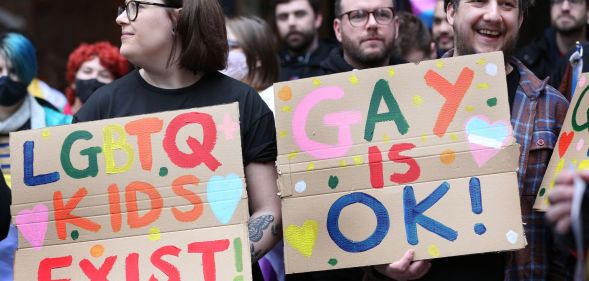 Members of the counter-protest at Colchester Library hold up signs in support of LGBTQ+ kids.