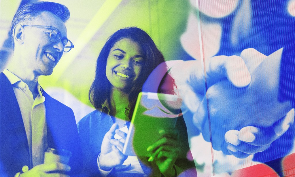 A male and female colleague look at a tablet.