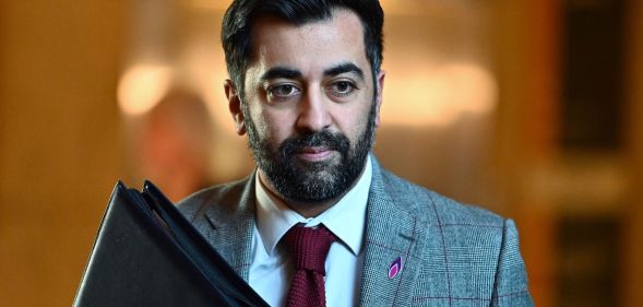 Humza Yousaf walking down a hall.