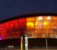 A photo showing the OVO Hydro Arena in Glasgow illuminated in lesbian Pride flag colours