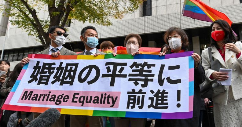 LGBTQ+ activists hold up a sign in protest of Japan's ban on marriage equality.