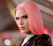 Jeffree Star looks at the camera wearing a pink straight wig, dark top and white necklace.