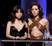 Jenna Ortega in a sparkly black top and Aubrey Plaza in a gold cross strap top, presenting at the 2023 SAG Award. Both actresses have a deadpan expression.