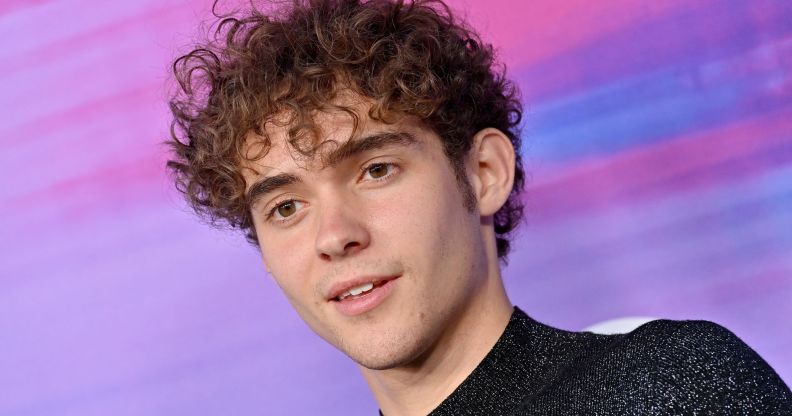 Joshua Bassett in front of a blue, pink and purple background.