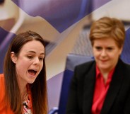 Kate Forbes pictured with Nicola Sturgeon in the background. The background of the image has been edited so the pair are pictured against a Scottish flag.