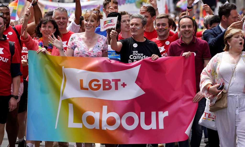 A photo showing LGBT+ Labour at Pride marching amongst a large crowd as they hold a banner that says "LGBT+ Labour"