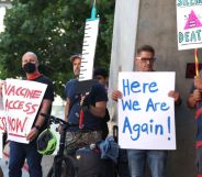 The LGBTQ+ community comes together for a protest about monkeypox. People hold signs that say "here we are again" and imploring the government to get more vaccines.