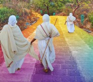 Jains wearing white robes walk down steps coloured in the LGBT Pride flag