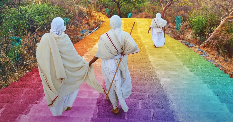 Jains wearing white robes walk down steps coloured in the LGBT Pride flag