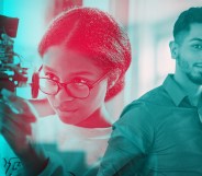 A woman is inspecting a piece of machinery. Next to her is a man looking at the camera.