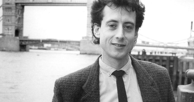 Peter Tatchell in a photograph promoting his candidacy in the 1983 Bermondsey by-election. He is pictured by a bridge wearing a suit in a black and white shot.