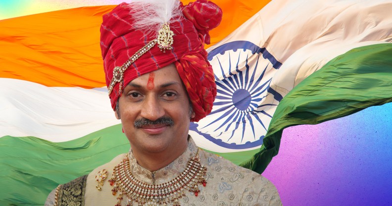 Prince Manvendra Singh Gohil, a smiling man wearing a gold top, red jewelled necklace and red turban with a feather.