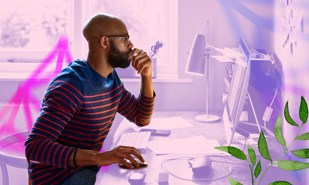 A man is working at his computer on top of a purple tinted home office setup.