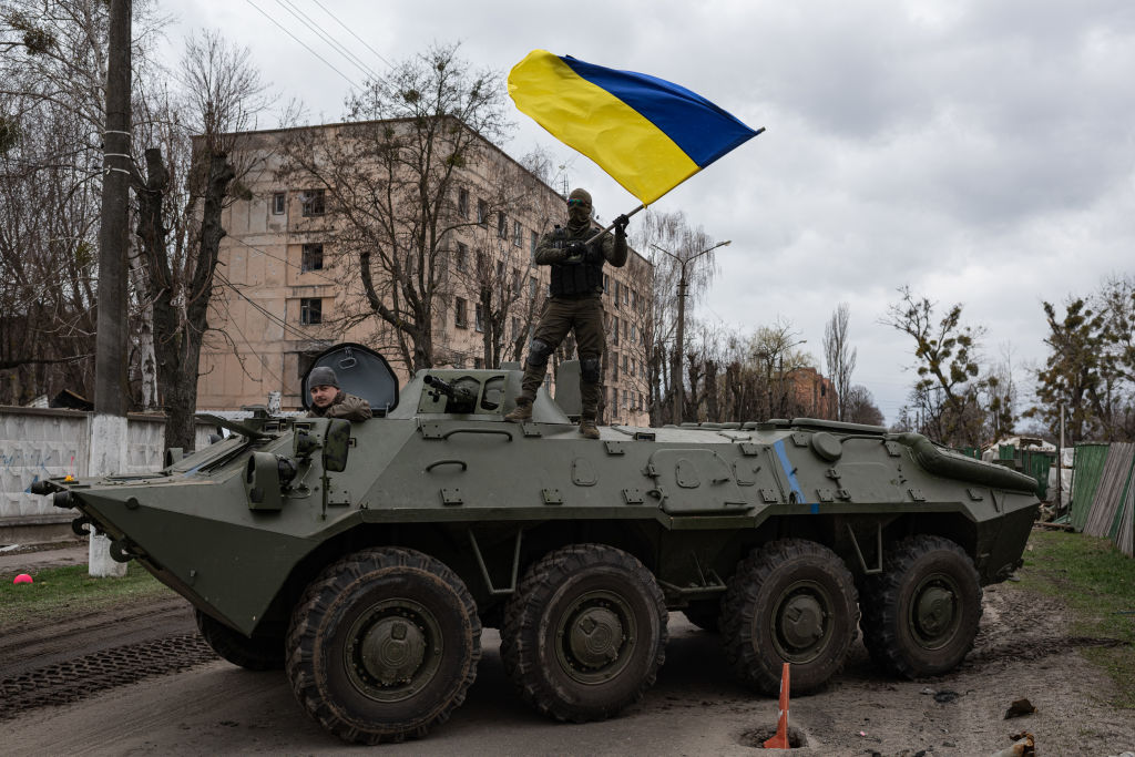 Ukrainian soldier waves Ukrainian national flag while standing on top of an armoured personnel carrier on April 8, 2022. 