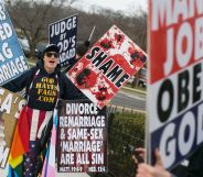 A member of the Westboro Baptist Church holding up various hateful signs.