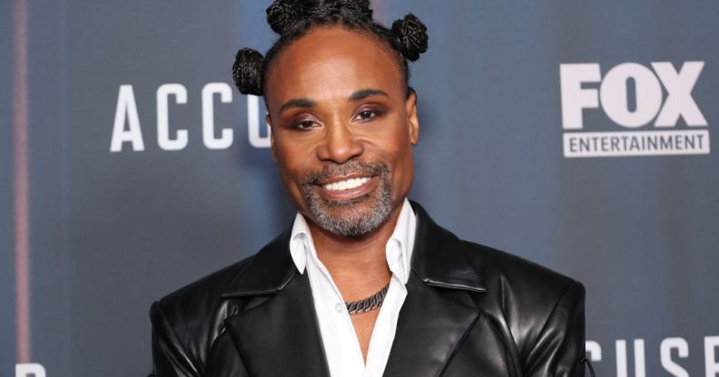 Billy Porter with his hair in bantu knots, wearing a white shirt and leather jacket