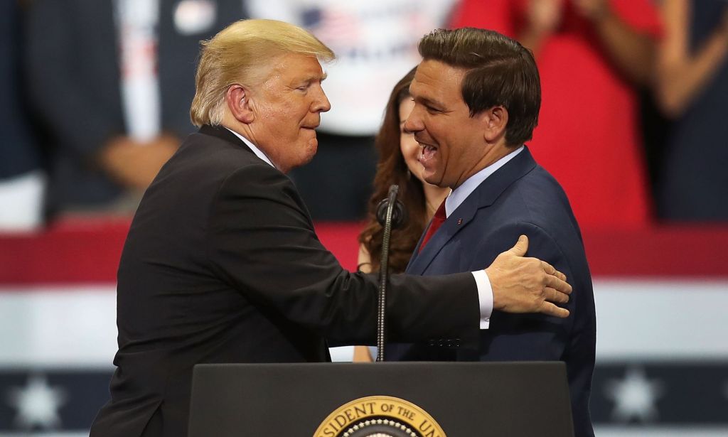 Republicans Donald Trump and Ron DeSantis hug as they speak at a rally