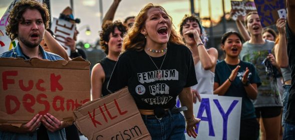 LGBTQ+ rights supporters protest against Florida Governor Ron Desantis, holding up signs criticising DeSantis and his support of the state's 'Don't Say Gay' legislation