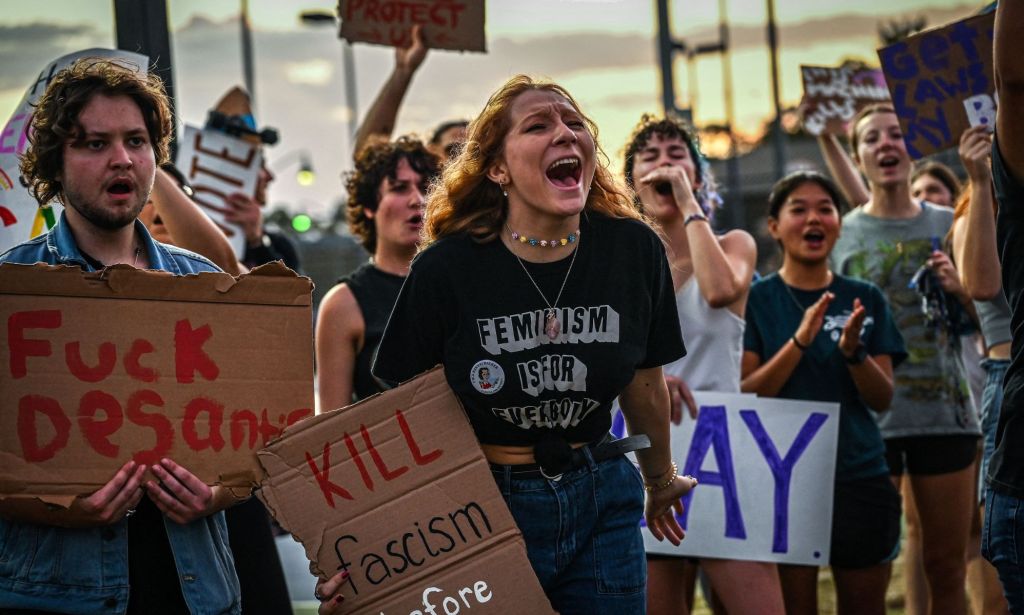 LGBTQ+ rights supporters protest against Florida Governor Ron Desantis, holding up signs criticising DeSantis and his support of the state's 'Don't Say Gay' legislation