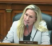 Marjorie Taylor Greene wears a black top and white patterned blazer as she sits at a House committee hearing