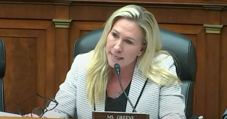 Marjorie Taylor Greene wears a black top and white patterned blazer as she sits at a House committee hearing