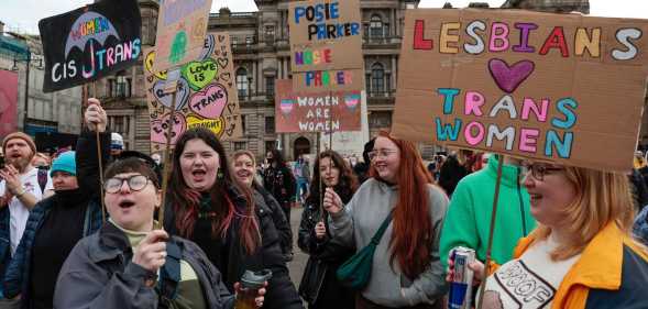 A photo showing trans rights protesters in Glasgow holding placards with messages saying "Lesbians love trans women"