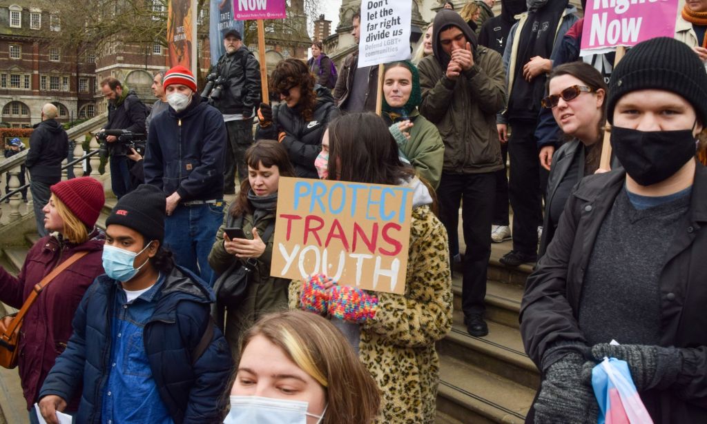 A person holds up a sign reading "protect trans youth" during a protest in support of the trans community