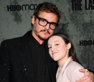 Pedro Pascal in a black suit and black glasses hugging Bella Ramsey, who is smiling and wearing a light pink suit.