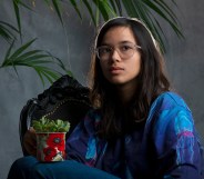 Pippa sitting, holding a potted succulent on their knee