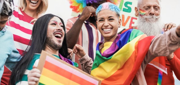 A group of LGBTQ people celebrating Pride and waving rainbow flags